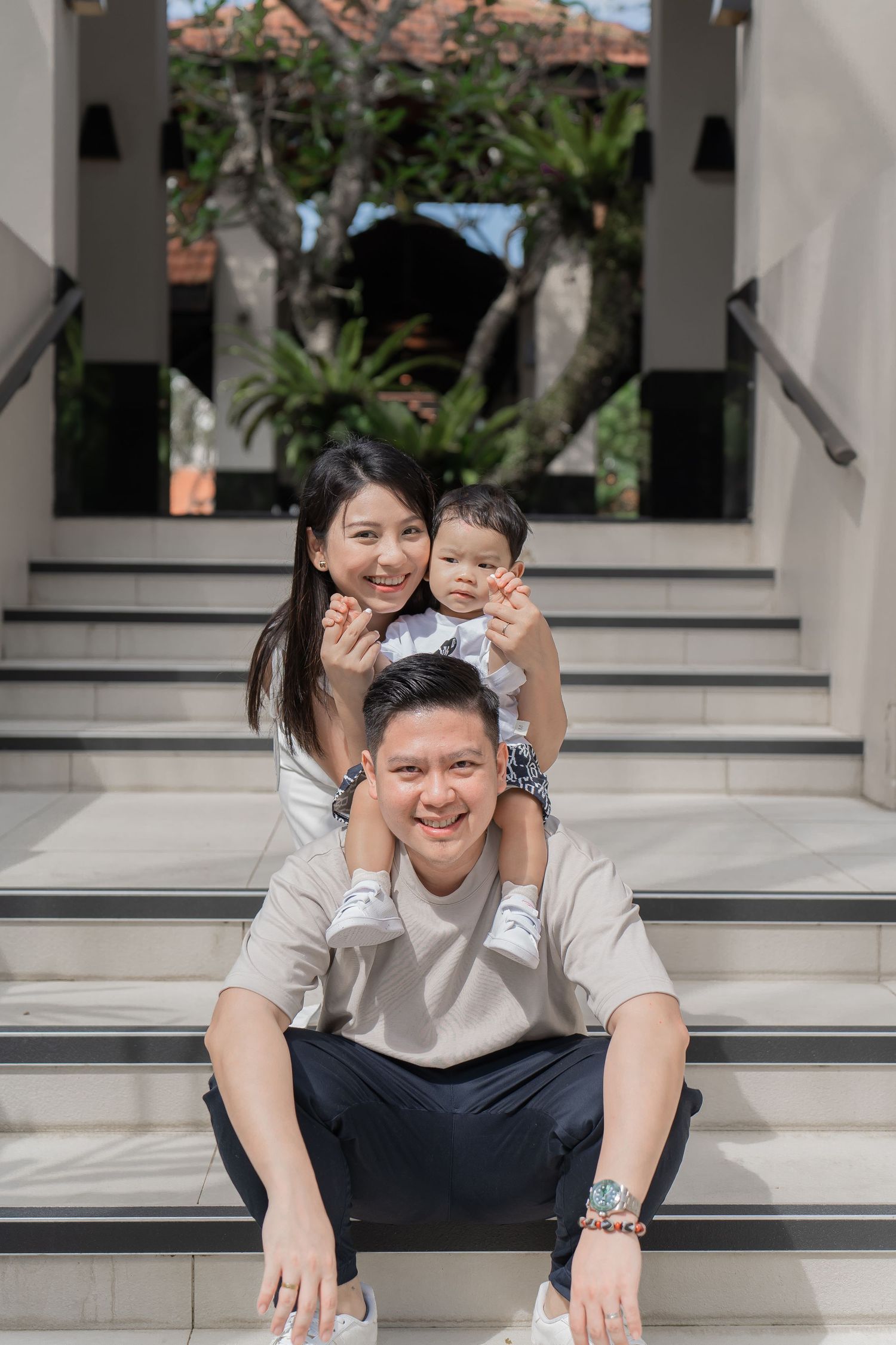 Family poses playfully on white stone steps in casual outfits.