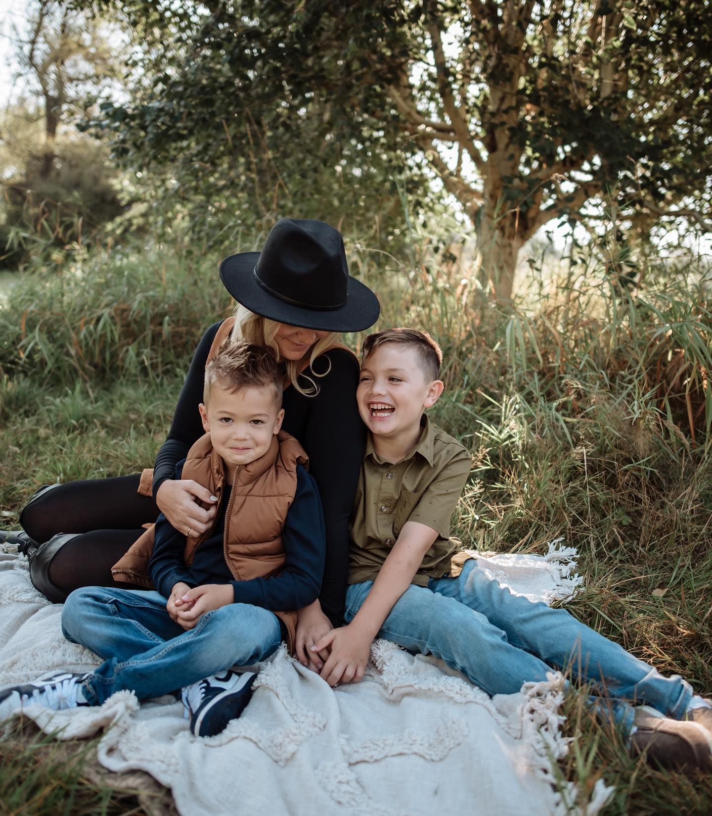 A family sits together on a blanket outdoors during a golden hour photoshoot in nature.