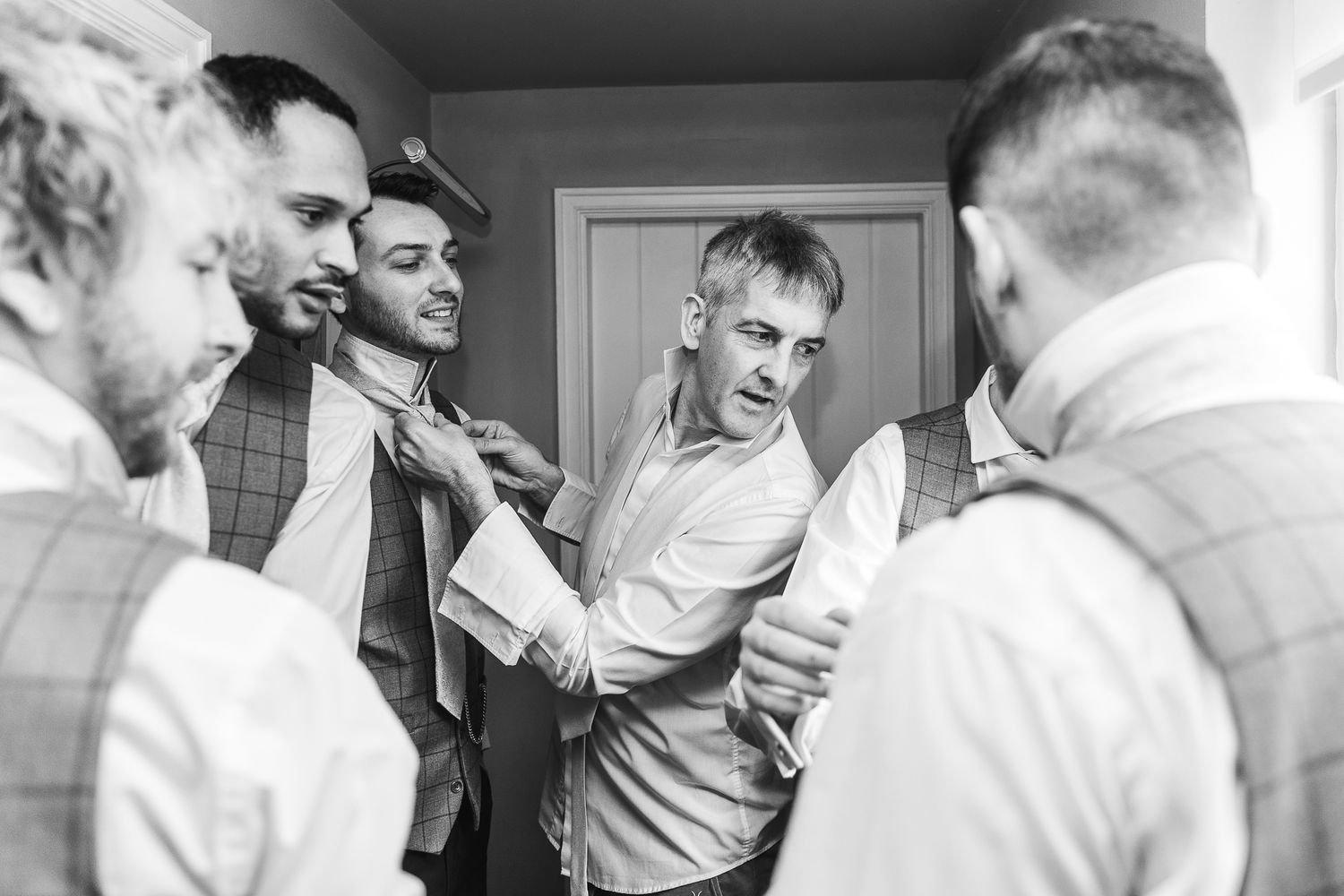 Black and white candid shot of groomsmen laughing and joking while getting ready.