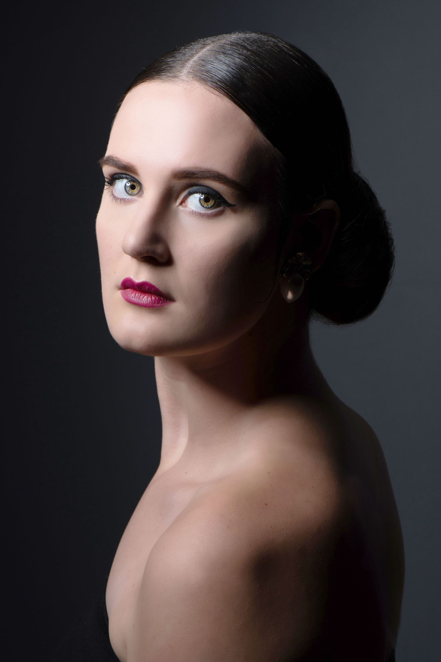 Artistic studio portrait with dramatic side lighting and classic beauty styling.
