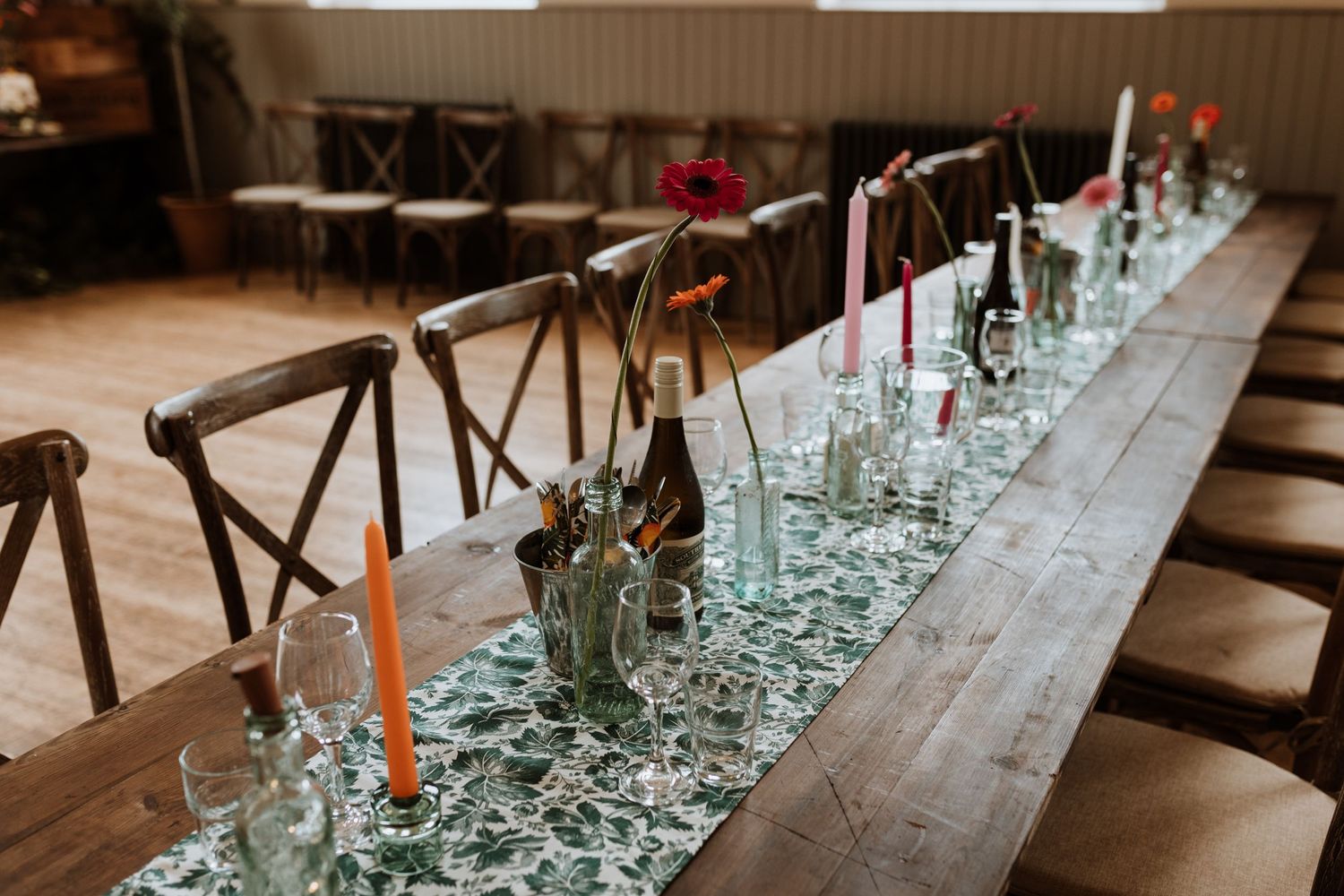 Table scape with orange and pink candles and green patterns runners