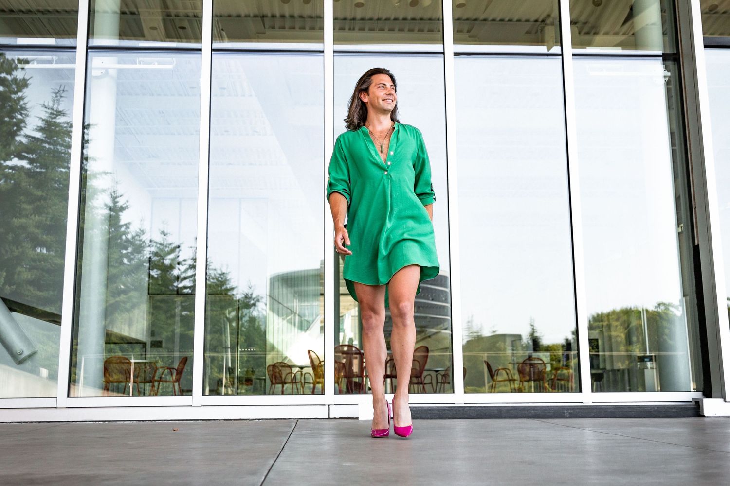 Inclusive photo session @ Seattle's Sculpture Park: she is wearing a green dress, pink heels in front of mirrored glass.
