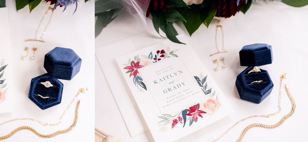 Navy blue velvet ring boxes and wedding invitations with floral design on white background.