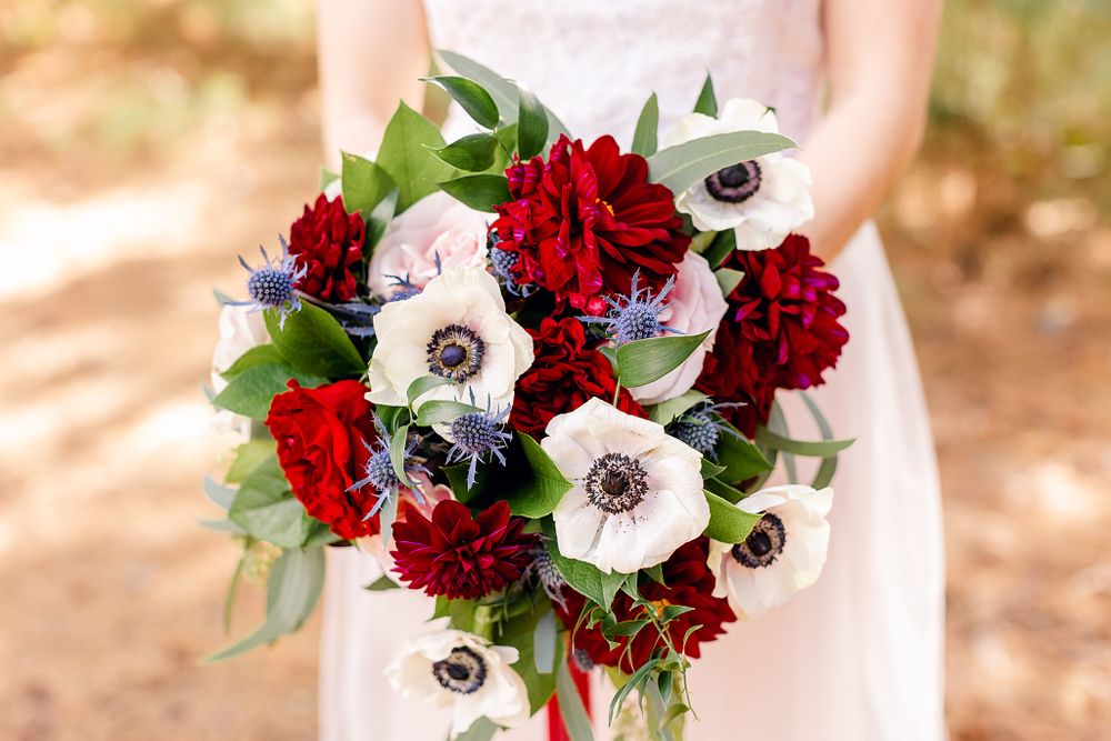 Stunning bridal bouquet featuring red roses, white anemones, and fresh greenery.