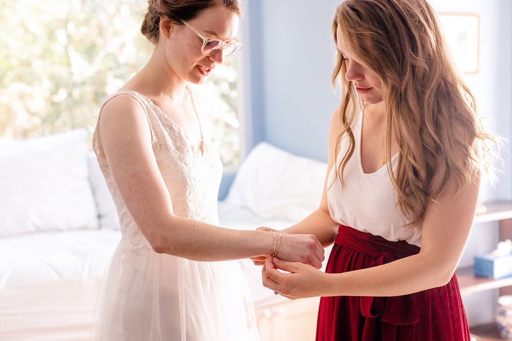 Two people in white and red outfits examining something together in a bright room.