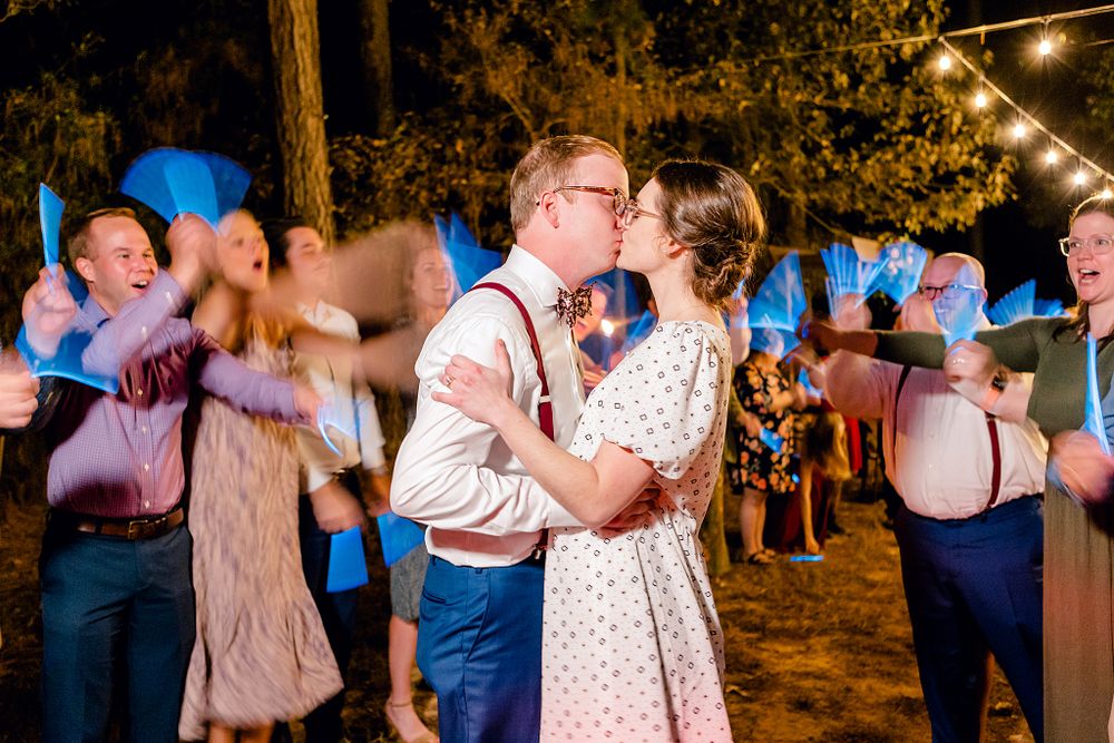 A couple dancing surrounded by guests at a rustic outdoor wedding reception.