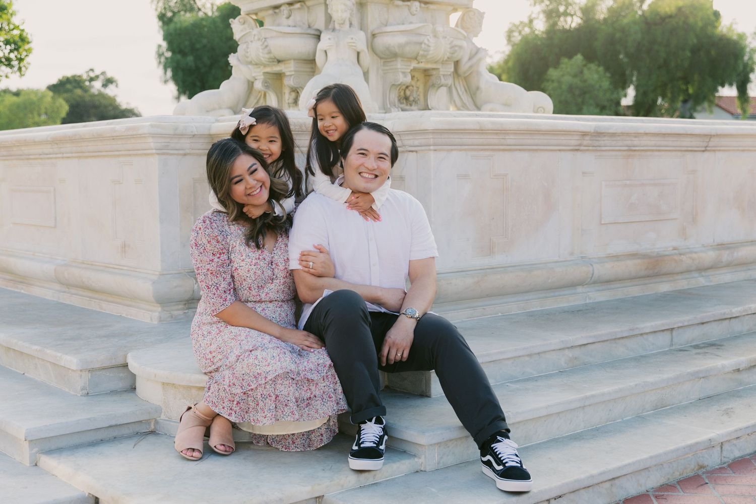 A family group poses casually on decorative white stone steps outdoors.