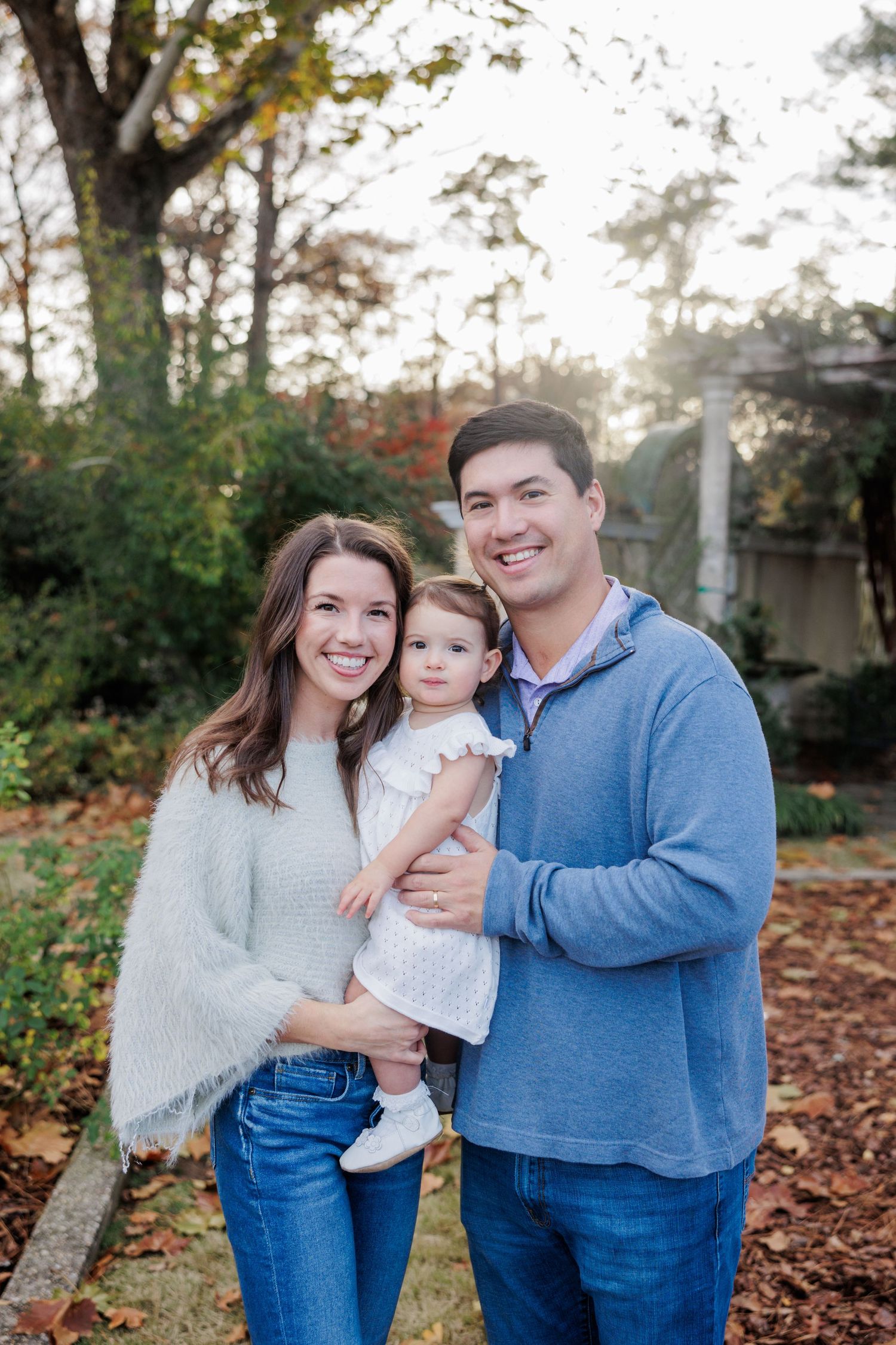Fall family portrait captured outdoors with autumn foliage in the background.