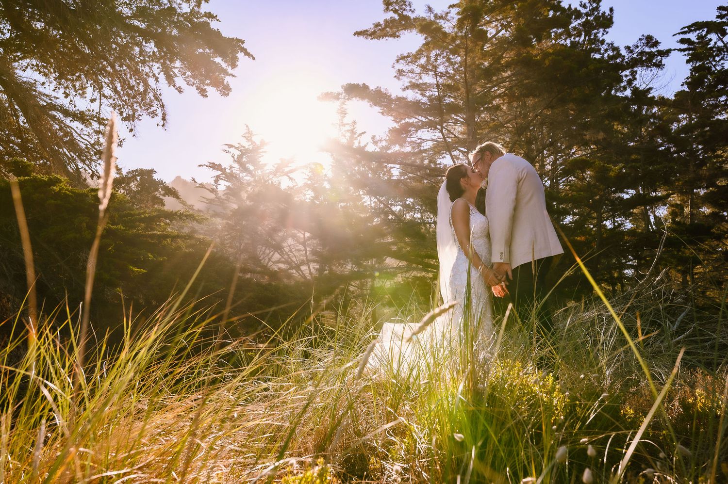 Silhouette of newlyweds standing together against sunset in scenic outdoor location.