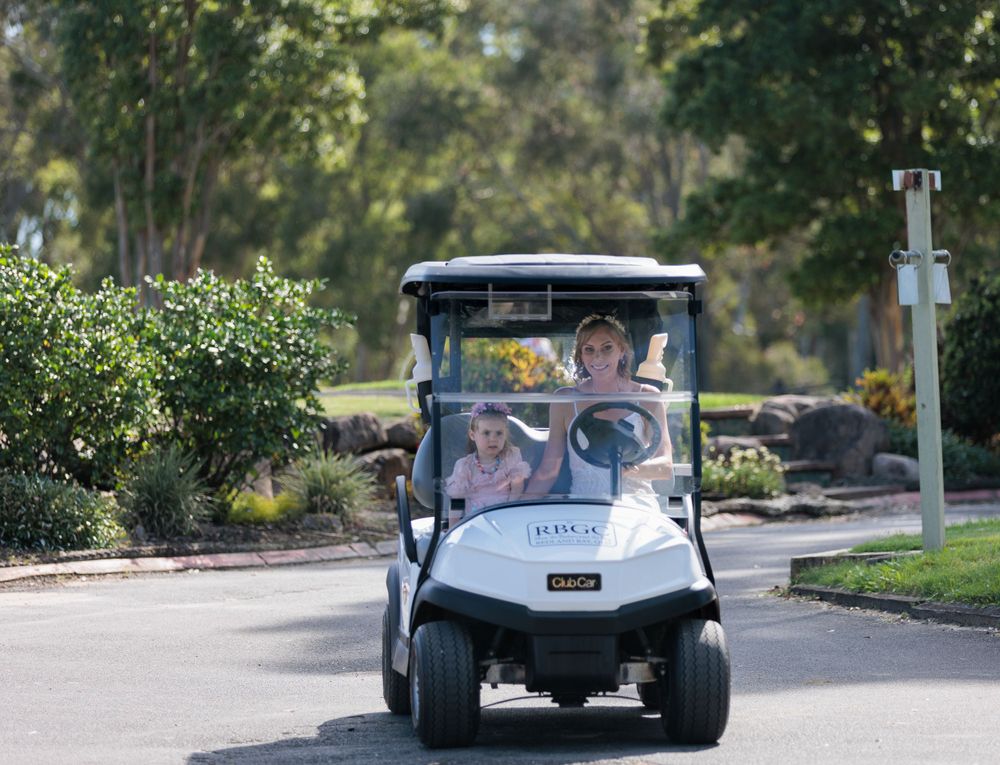 Golf cart driving down a winding path surrounded by lush greenery.
