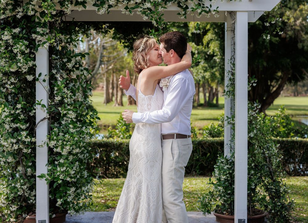 Wedding ceremony under a white pergola decorated with green vines and natural foliage. Redlands