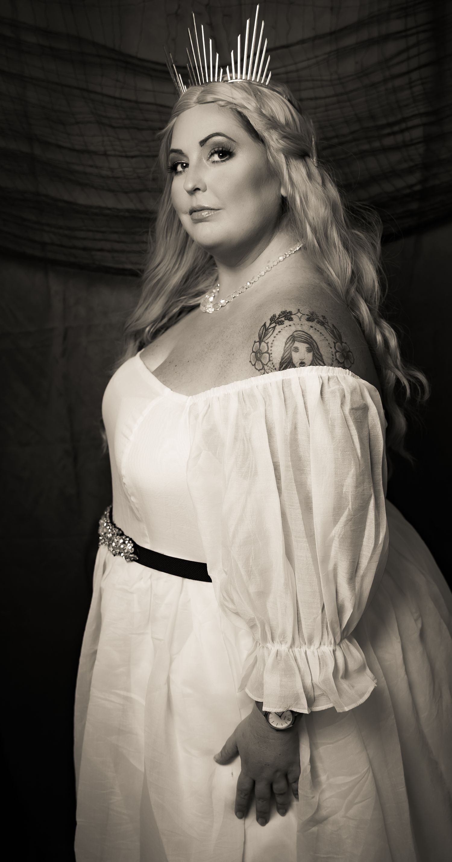 Dramatic black and white portrait featuring an ethereal white dress and crown.