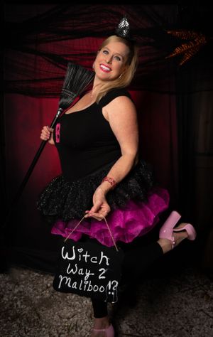 Witch-themed portrait with black tulle skirt and purple accents on stone floor.