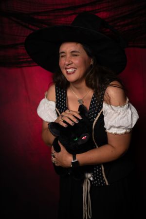 A witch-themed costume photoshoot with black dress and wide-brimmed hat.