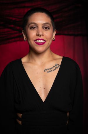 Artistic portrait with black top against deep red backdrop showing emotional expression.