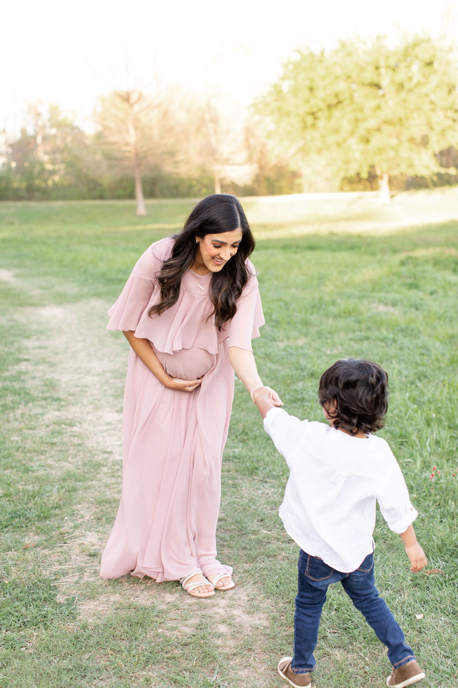 A touching moment between parent and child in a sun-dappled park setting.