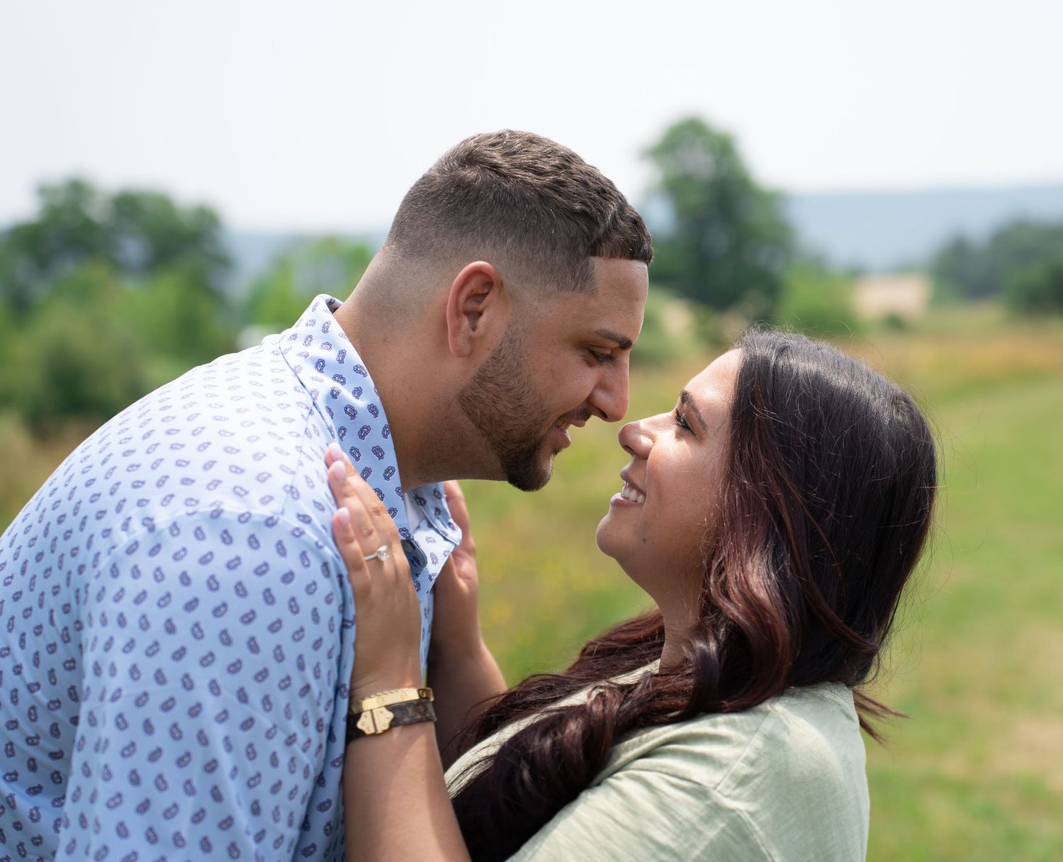 Romantic couple shares intimate moments in a grassy field during golden hour.