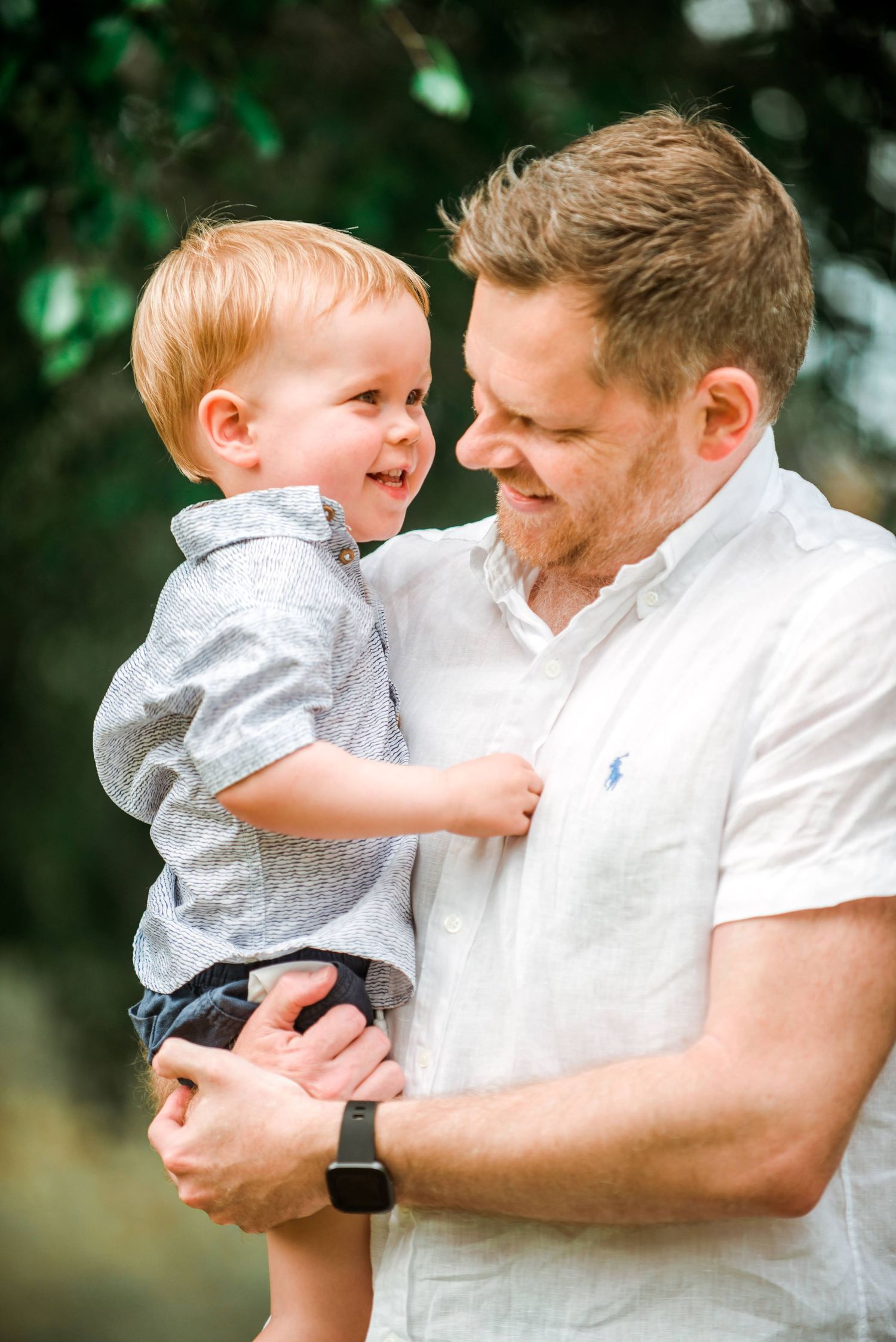 Joyful parent and toddler laughing together during outdoor photoshoot.