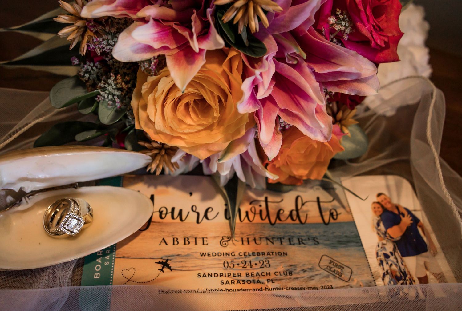 Colorful wedding bouquet with pink and orange flowers beside a wedding invitation for Abbie and Hunter.
