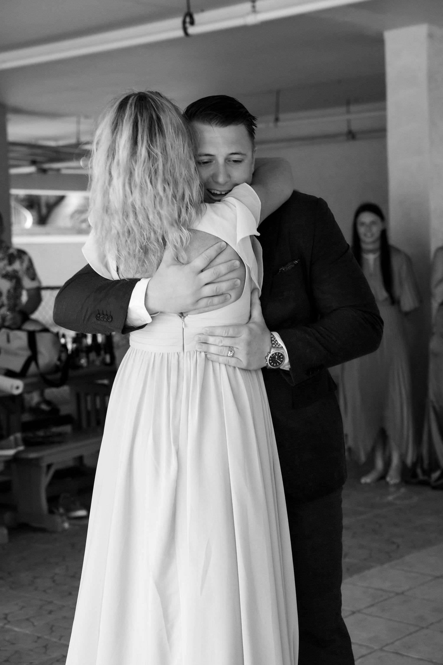 Black and white photo of groom hugging bride during intimate wedding reception dance.