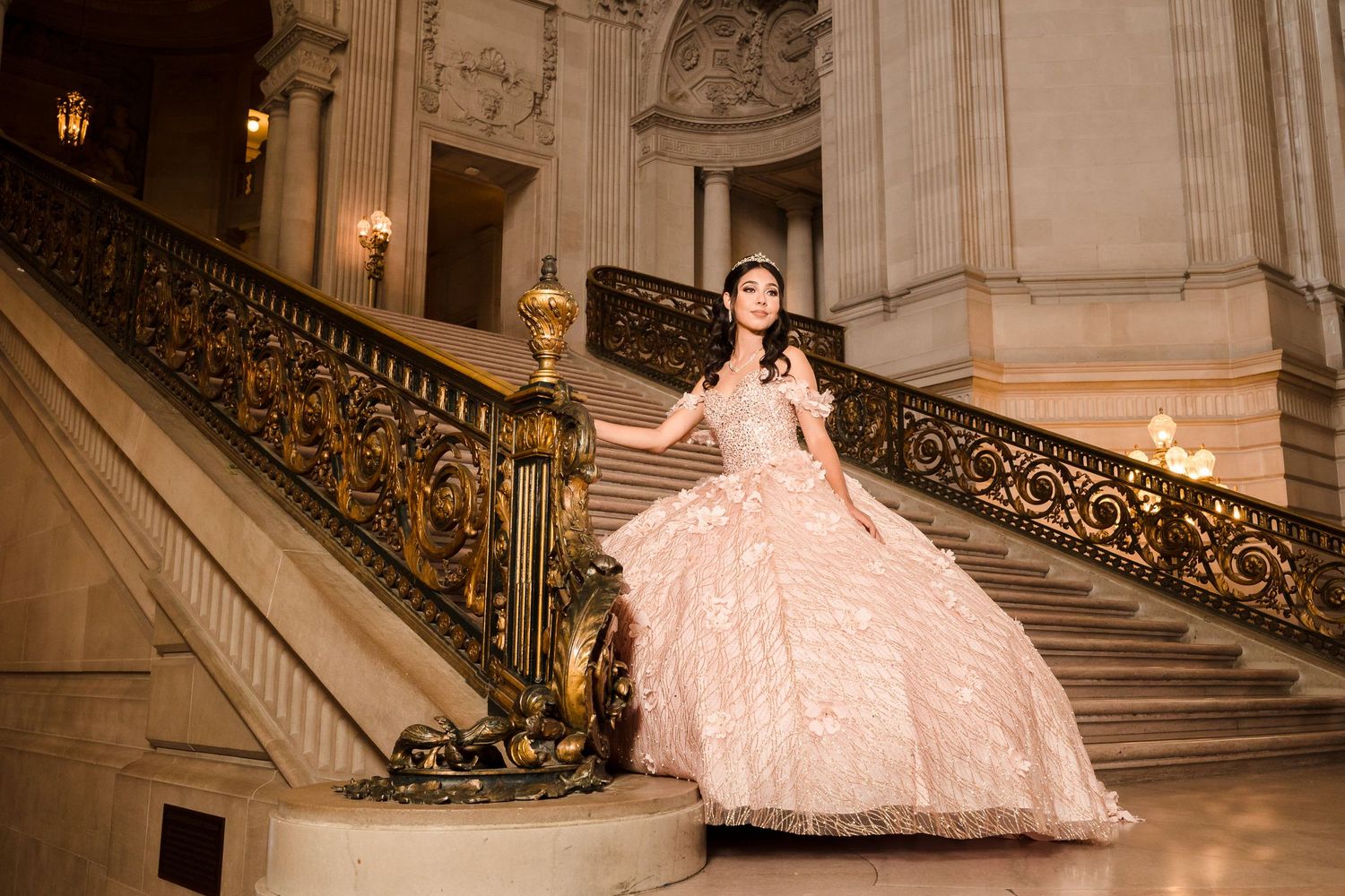 Elegant ballgown dress pose on grand staircase with ornate gold railings.