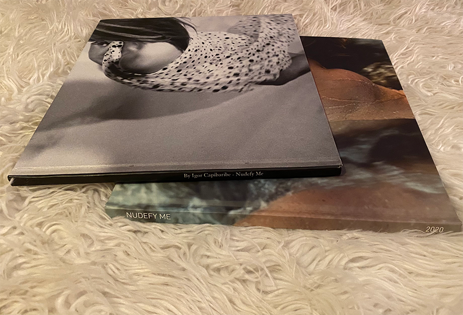Art books displayed on white textured carpet creating a monochromatic composition.