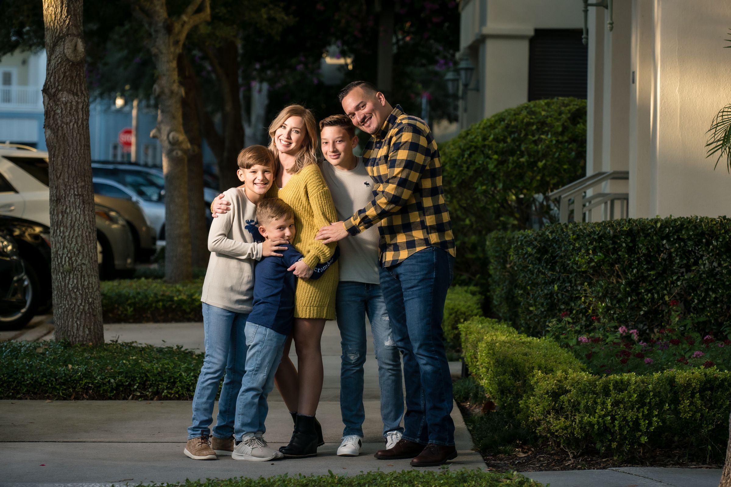 A family group shares a happy moment together outside their home in evening light.