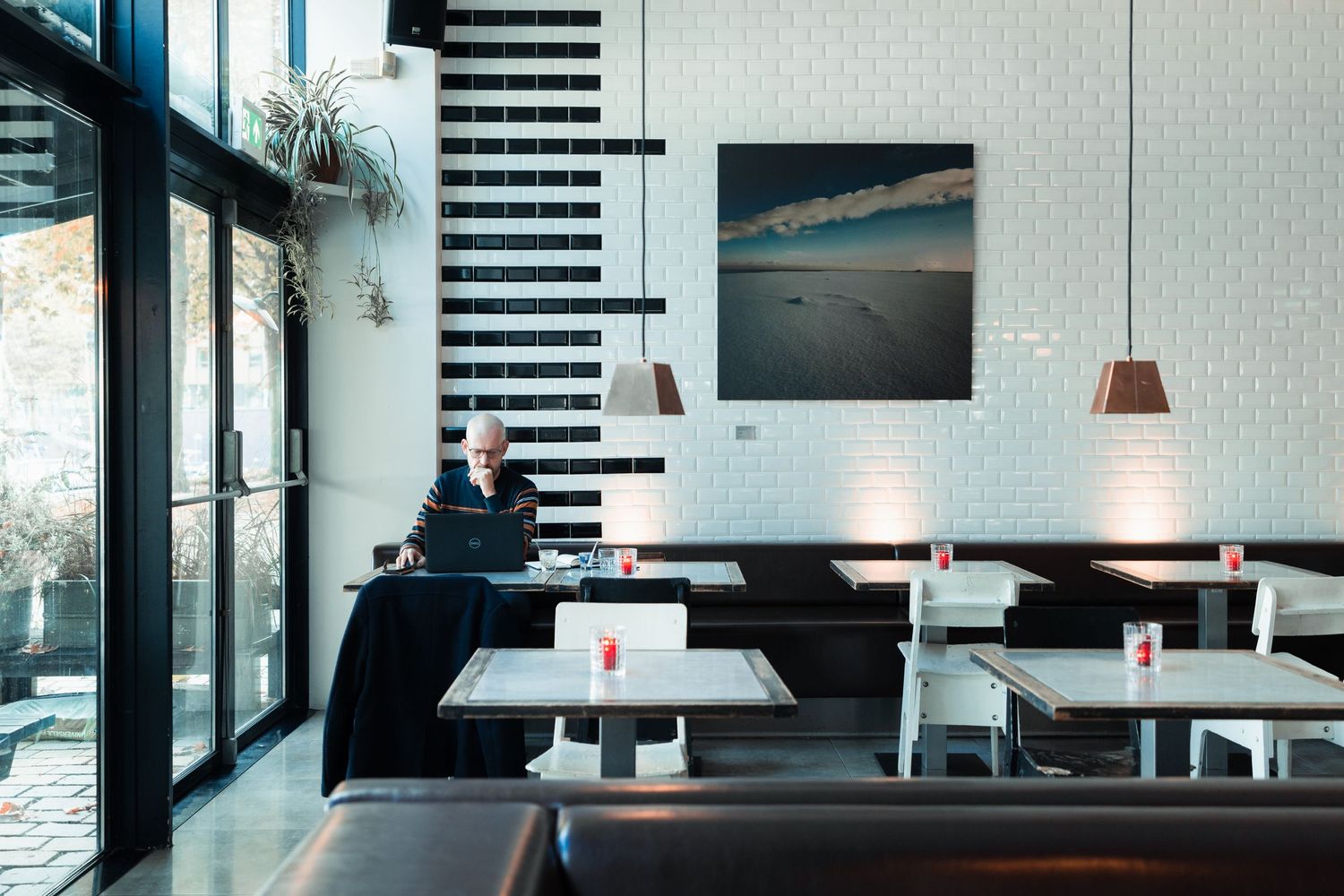 Modern cafe interior with black and white design featuring stairs and pendant lighting.