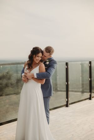 An intimate moment between newlyweds embracing on a modern deck with mountain vistas.