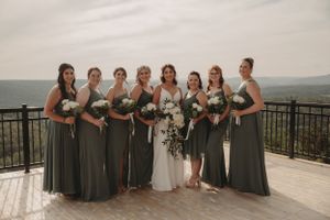 Bridal party in elegant grey dresses poses on scenic mountain overlook.