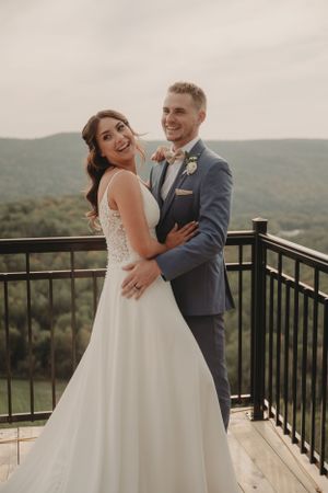 Joyful wedding couple embraces while sharing a romantic moment on an outdoor viewing deck.