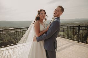 Intimate moment between newlyweds on outdoor terrace with rolling hills in background.