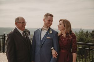 Wedding party gathers on scenic overlook deck for formal portrait during celebration.