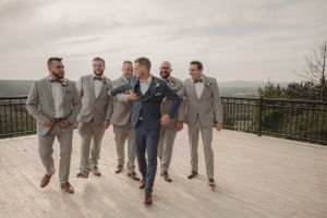 Groomsmen celebrating with fun group poses on mountain venue terrace.