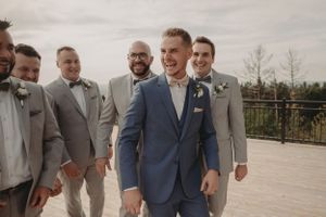 Wedding party shares laughs and candid moments in coordinated suits.