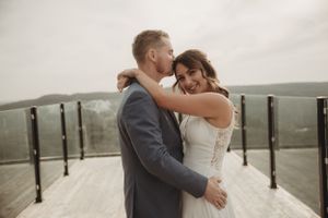 A romantic embrace between newlyweds on a scenic balcony overlooking natural landscape.