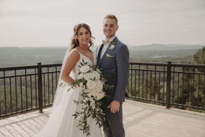 An elegant wedding portrait with panoramic mountain views and white floral bouquet.