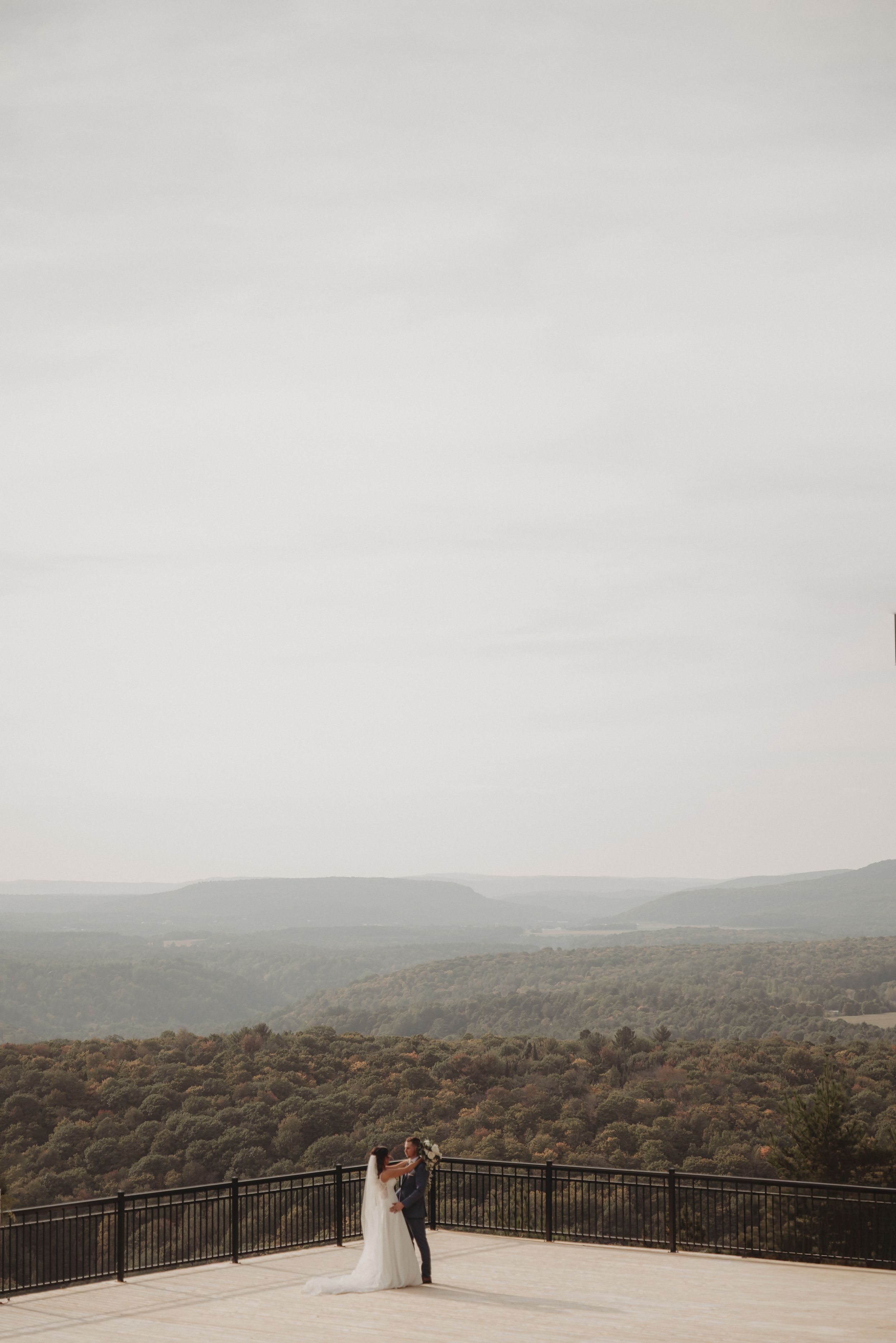 A scenic wedding portrait on a mountain overlook with sweeping valley views.