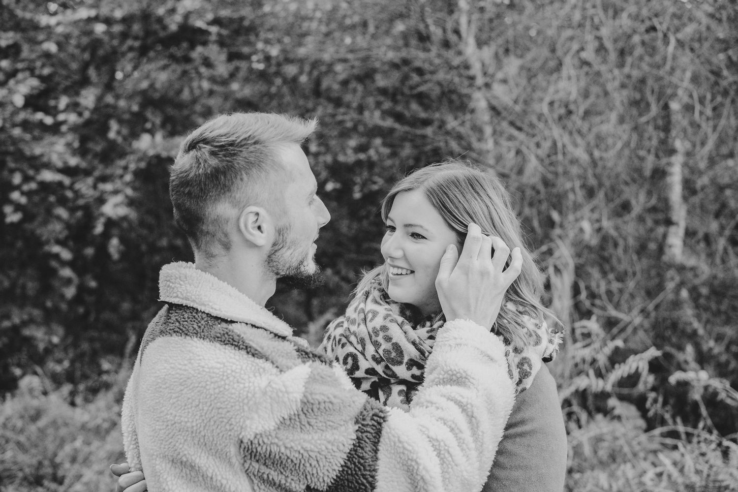 A tender black and white portrait of a couple sharing an emotional moment outdoors.