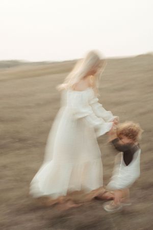 Artistic motion blur captures dancing moment between parent and child in field.
