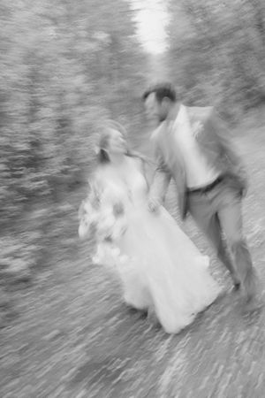 An artistic motion blur captures a couple dancing in wedding attire outdoors.