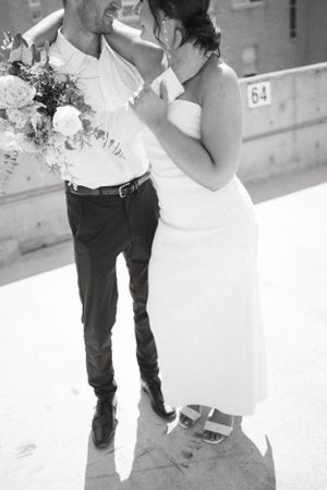 Black and white wedding portrait showing intimate embrace with floral bouquet.