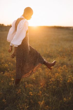 Person in a polka dot dress twirling in a sunlit field at golden hour.