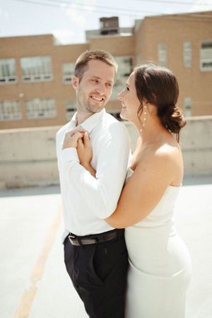 Romantic rooftop wedding moment with bright sunlight and urban backdrop.