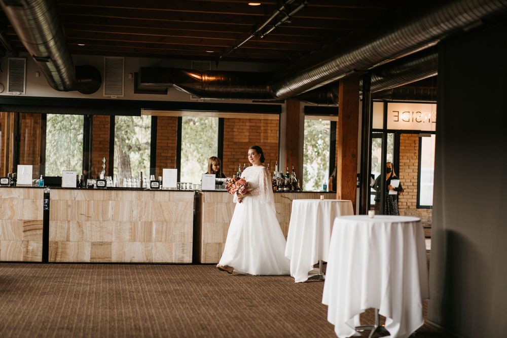 Bride in a white gown holding a bouquet standing in a modern wedding venue.