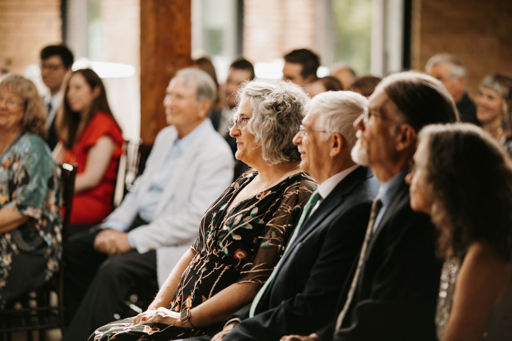 Smiling wedding guests seated together, including an older couple laughing joyfully during the ceremony.