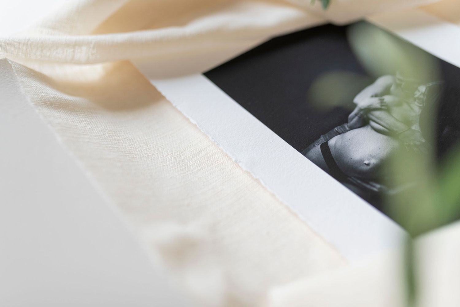 Close-up of black and white maternity photo partially wrapped in cream silk ribbon.
