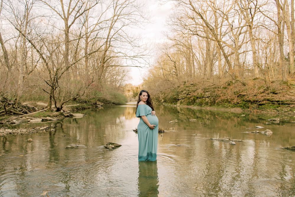 Expecting mother standing gracefully in a creek, surrounded by nature, capturing the serene beauty of her maternity journey.