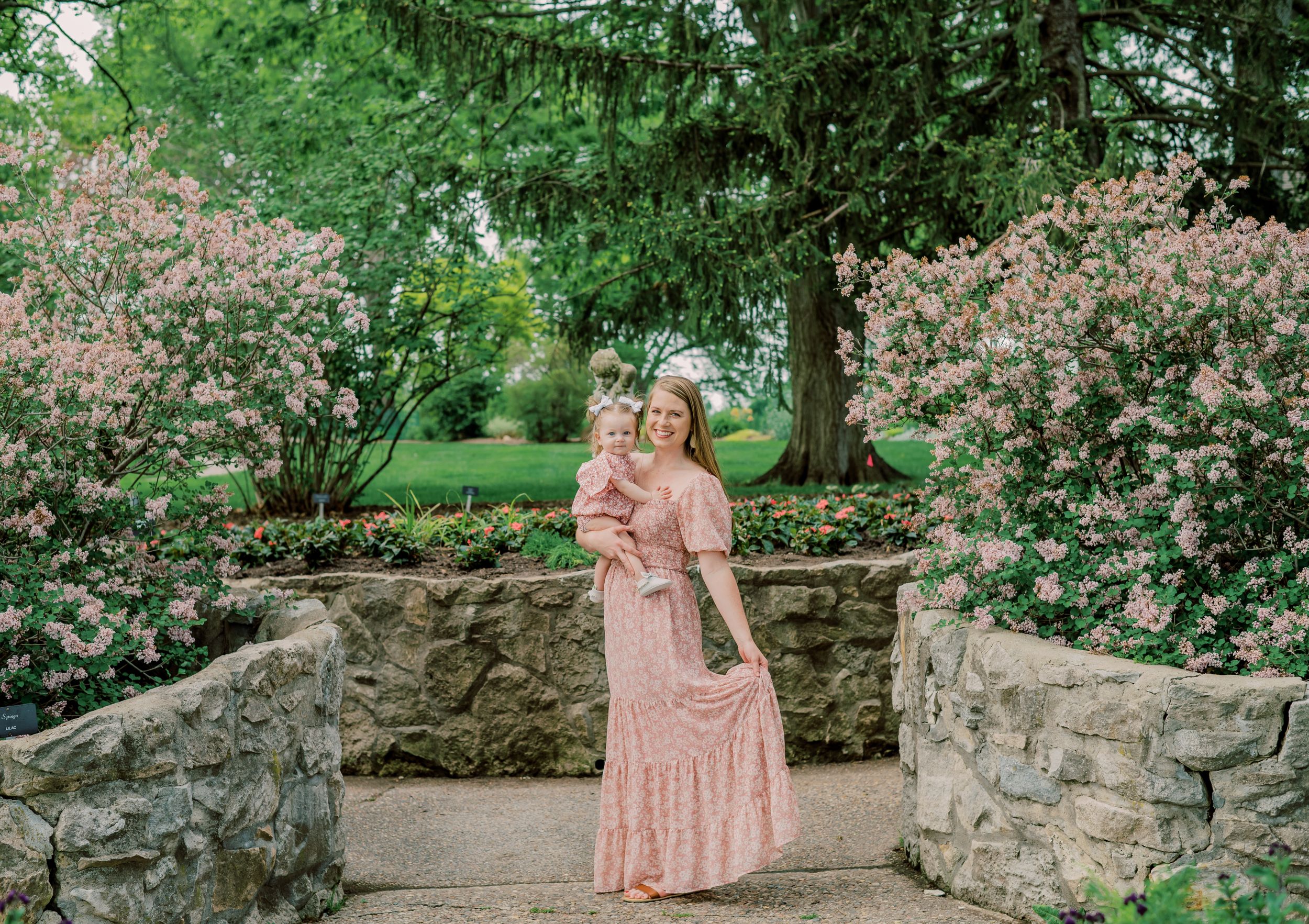 Mom & daughter sharing a sweet moment in a public garden, surrounded by blooming roses, capturing the beauty of their bond