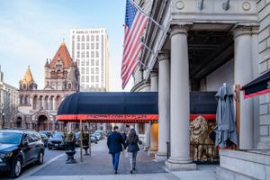 View of Trinity Church and Copley Square in Boston with pedestrians and an American flag.